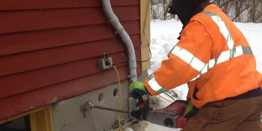A contractor performing foundation repair work on a house in winter conditions, representing Ottawa foundation repair contractors addressing structural issues.