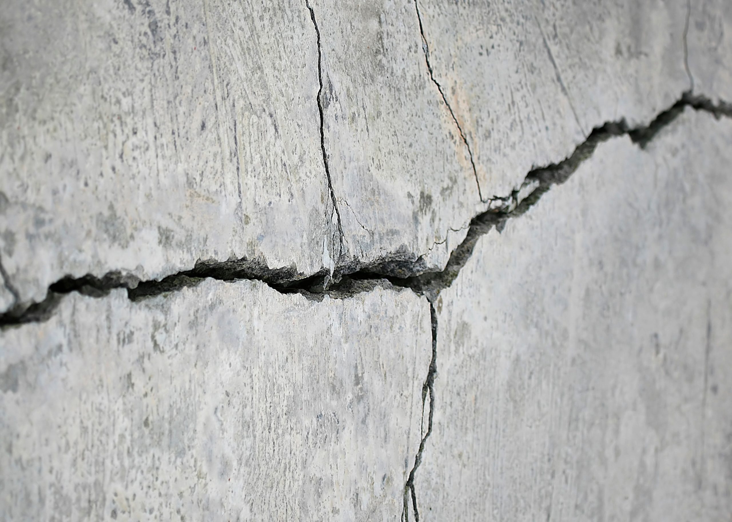 Close-up of a cracked concrete, showcasing damage caused by wear and settlement, highlighting the need for concrete repair.