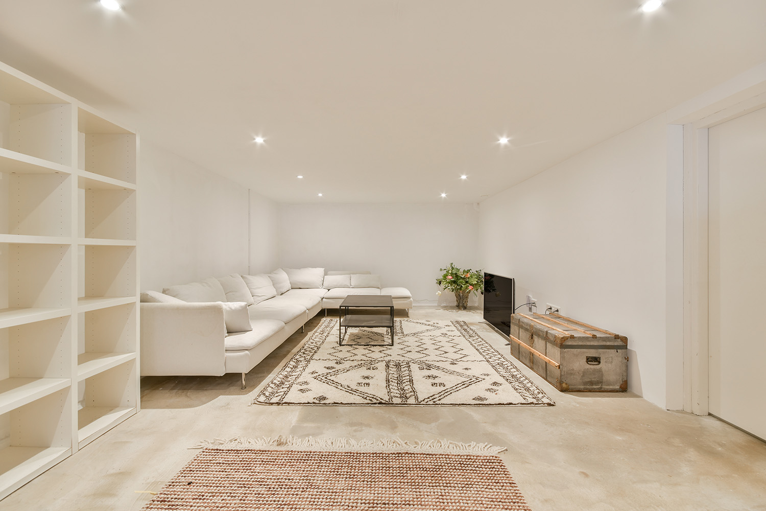 Spacious, newly renovated basement with light-colored flooring, a fireplace, and double doors leading outside, highlighting the results of a basement lowering and remodeling project in Ottawa, Gatineau, or Kingston.